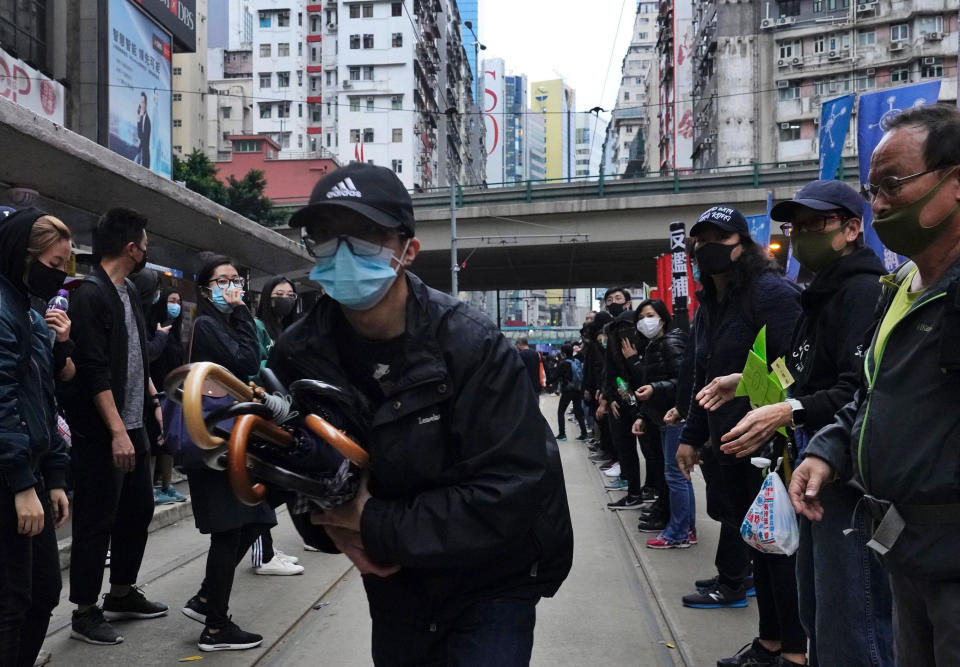 Protestors pass on umbrellas to front line protestors during their annual pro-democracy march on New Year's Day in Hong Kong, Wednesday, Jan. 1, 2020. Hong Kong toned down its New Year’s celebrations amid the protests that began in June and which have dealt severe blows to the city’s retail, tourism and nightlife sectors. (AP Photo/Vincent Yu)