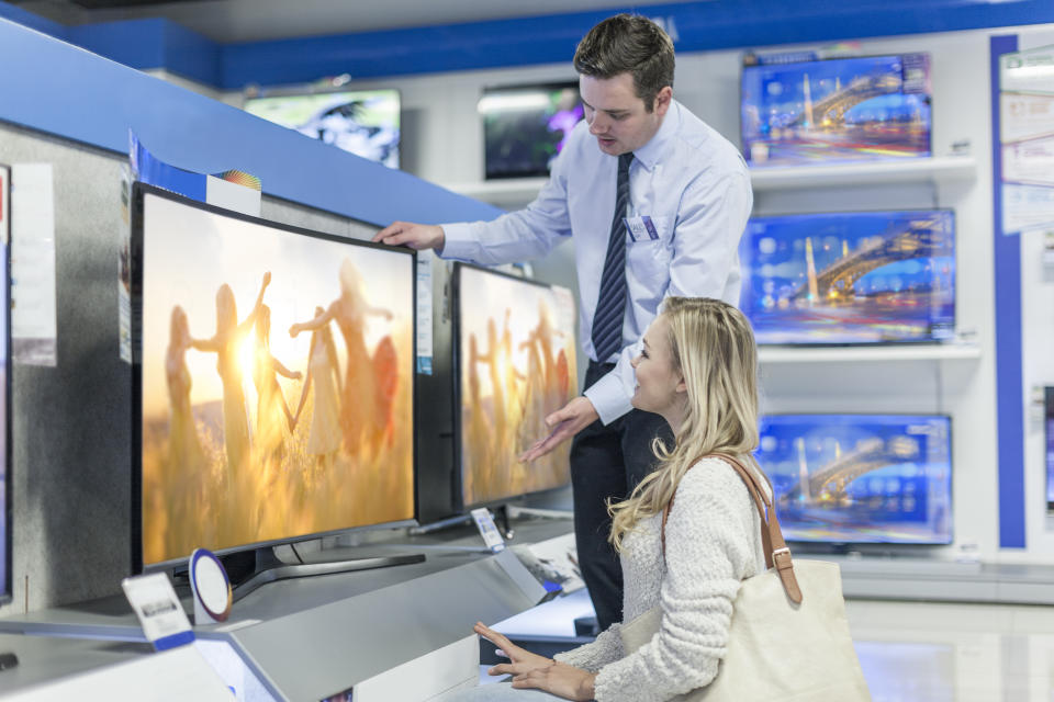 Shop assistant showing flatscreen TV to customer