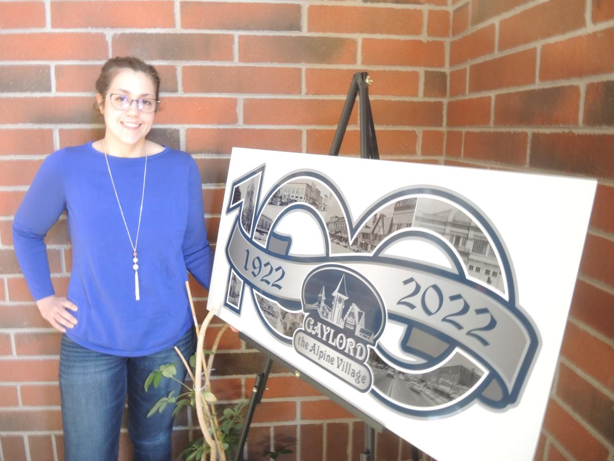 Erika Peters stands next to the graphic design marking the 100th anniversary of Gaylord attaining city status this year. She is coordinating all city events that will mark the occasion for the city. It all starts on May 28 at the Pavilion during the Strolling into Summer event.