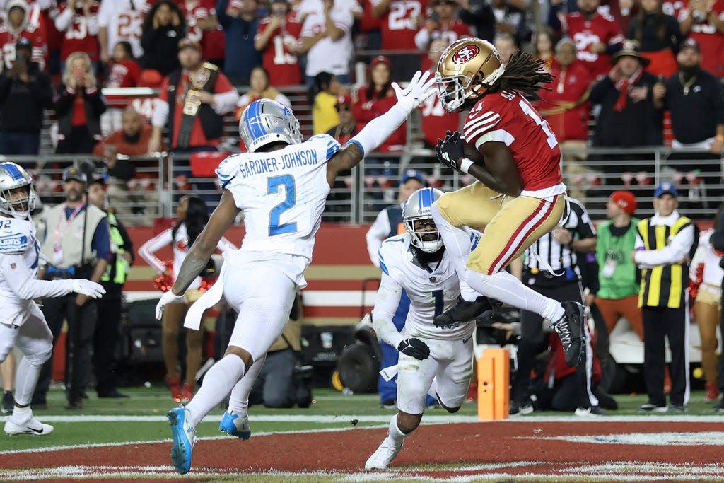 San Francisco 49ers wide receiver Brandon Aiyuk, top right, catches a touchdown pass against Detroit Lions safety C.J. Gardner-Johnson (2) and cornerback Cameron Sutton (1) during the second half of the NFC Championship NFL football game in Santa Clara, Calif., Sunday, Jan. 28, 2024. (AP Photo/Jed Jacobsohn)