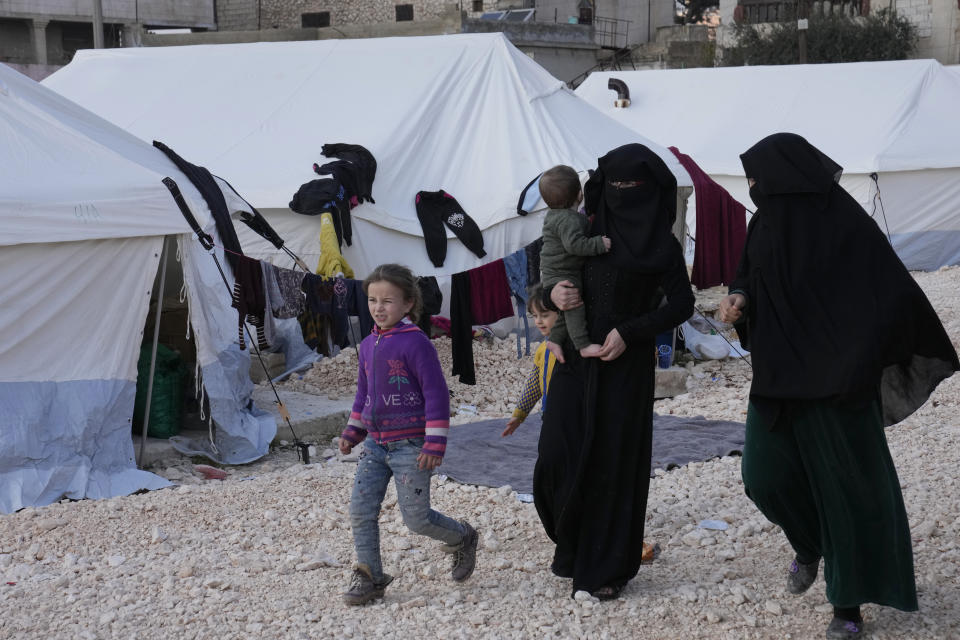 FILE - Women and children who lost their homes walk in among tents at a camp in Atareb, Syria, Sunday, Feb. 12, 2023. Women in particular have shouldered the responsibility of keeping shattered families together during the past 12 years of civil war. The massive earthquake that hit last week is the latest in a litany of hardships for Syrian women, many of whom have been left dependent on aid and alone responsible for their families' well-being. (AP Photo/Hussein Malla, File)