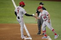 Los Angeles Angels' Jo Adell, left, celebrates his run-scoring single with first base coach Bruce Hines (99) in the seventh inning of a baseball game against the Texas Rangers as umpire Nick Mahrley stands by the bag in Arlington, Texas, Tuesday, Aug. 3, 2021. (AP Photo/Tony Gutierrez)