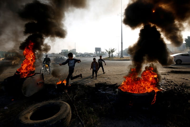 Iraqi boy runs between burning tires during ongoing anti-government protests in Najaf