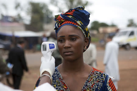 A health worker checks the temperature of a woman entering Mali from Guinea at the border in Kouremale October 2, 2014. REUTERS/Joe Penney