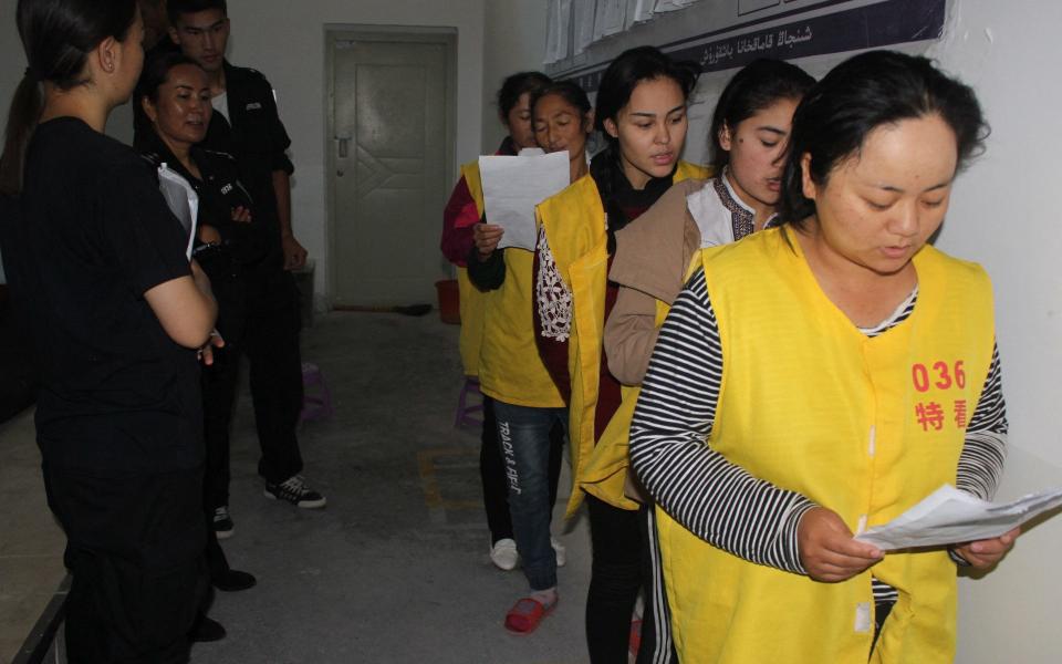 This undated handout image released by The Victims of Communism Memorial Foundation on May 24, 2022, shows detainees guarded by police as they stand in line apparently reciting or singing at the Tekes County Detention Centre in the Xinjiang Region of western China