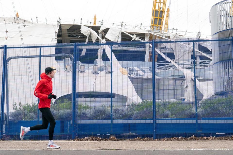 A runner passes the O2 Arena in London, which had part of its roof sheared off in the storm and forced its closure for the weekend (Dominic Lipinski/PA) (PA Wire)