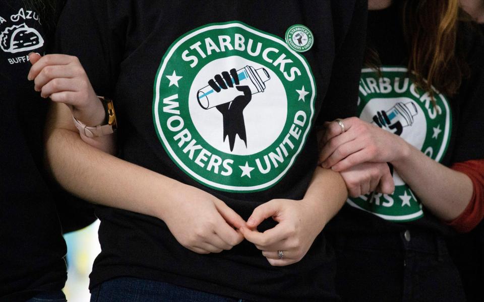 Starbucks employees and supporters link arms during a union election watch party