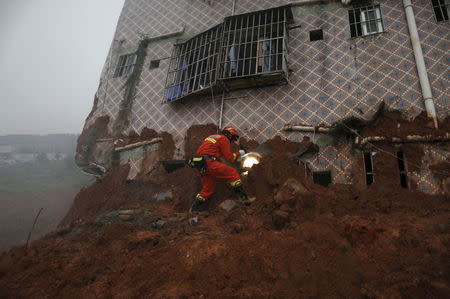 A firefighter uses a flashlight to search for survivors at a damaged building at the site of a landslide at an industrial park in Shenzhen, Guangzhou, China, December 20, 2015. REUTERS/Tyrone Siu