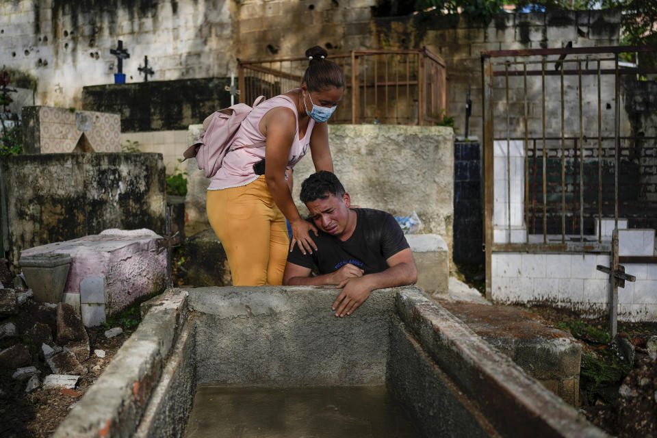 Johaniet Cartaya, a la izquierda, y su hermano Jorge Cartaya lloran después de enterrar en la misma tumba a su madre Yanet Rivas y a su tía Aimara Navas en Las Tejerías, Venezuela, el miércoles 12 de octubre de 2022. Las hermanas estaban entre las docenas que murieron cuando un deslizamiento de tierra causado por fuertes lluvias arrasó Las Tejerías en la noche del 9 de octubre. (AP Foto/Matías Delacroix)