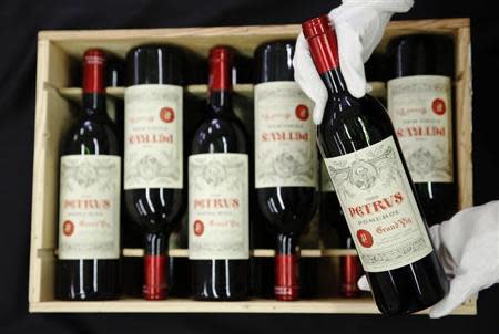 An employee poses with a case of twelve bottles of "Petrus 1988" wine owned by retired Manchester United boss Alex Ferguson, at Christie's auction house in London April 14, 2014. REUTERS/Luke MacGregor