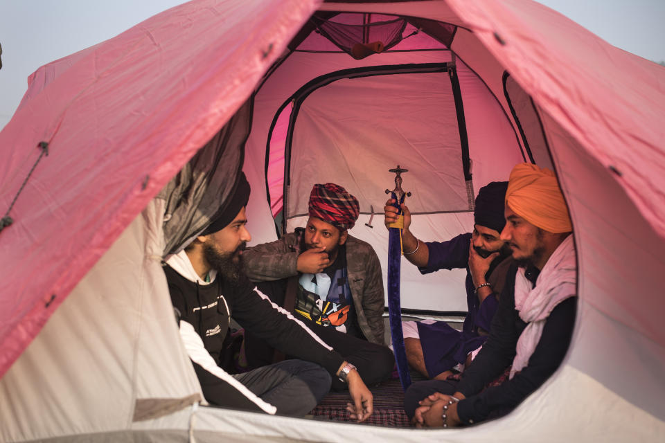 From left to right, Sahajpal Singh, Arjun Singh, Jagmohan Singh and Gurdayal Singh chat as they sit inside a tent pitched on a highway during a protest against new farm laws, at the Delhi-Haryana state border, India, Tuesday, Dec. 1, 2020. Instead of cars, the normally busy highway that connects most northern Indian towns to the capital is filled with tens of thousands of protesting farmers, many wearing colorful turbans. Their convoy of trucks, trailers and tractors stretches for at least three kilometers (1.8 miles). Inside, they have hunkered down, supplied with enough food and fuel to last weeks. (AP Photo/Altaf Qadri)