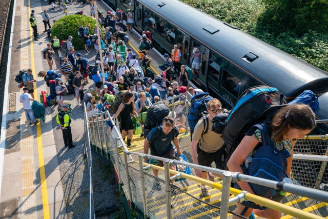 Revellers arrive at Castle Cary train station as they make their way off the platform and onto the buses that will shuttle them to Glastonbury Festival 