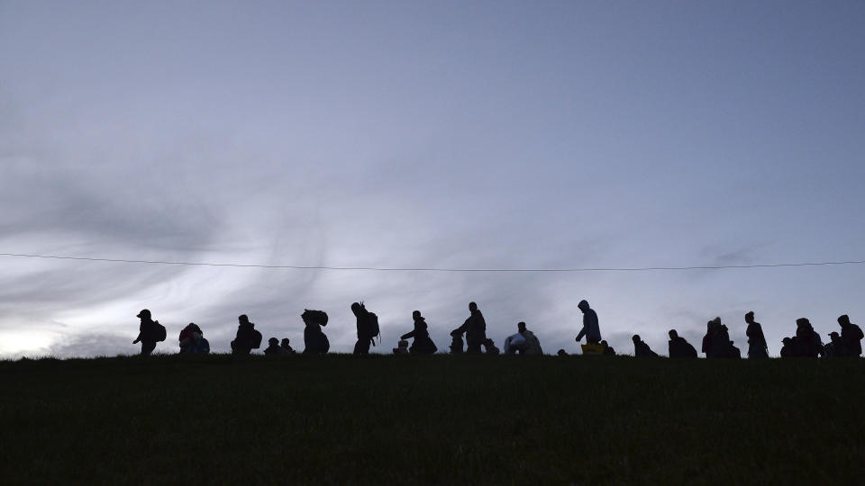 FILE - In this Wednesday, Oct. 28, 2015 file photo German federal police officers guide a group of migrants on their way after crossing the border between Austria and Germany in Wegscheid near Passau, Germany. Germany's population has contracted slightly for the first time in nearly a decade because immigration shrank as a result of the coronavirus pandemic, official data showed Tuesday. (AP Photo/Kerstin Joensson, file)