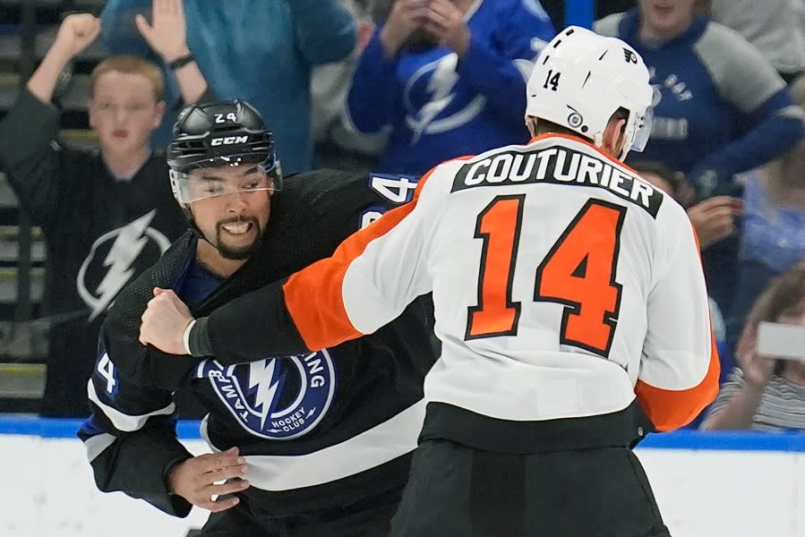 Tampa Bay Lightning defenseman Matt Dumba (24) and Philadelphia Flyers center Sean Couturier (14) fight during the second period of an NHL hockey game Saturday, March 9, 2024, in Tampa, Fla. (AP Photo/Chris O’Meara)