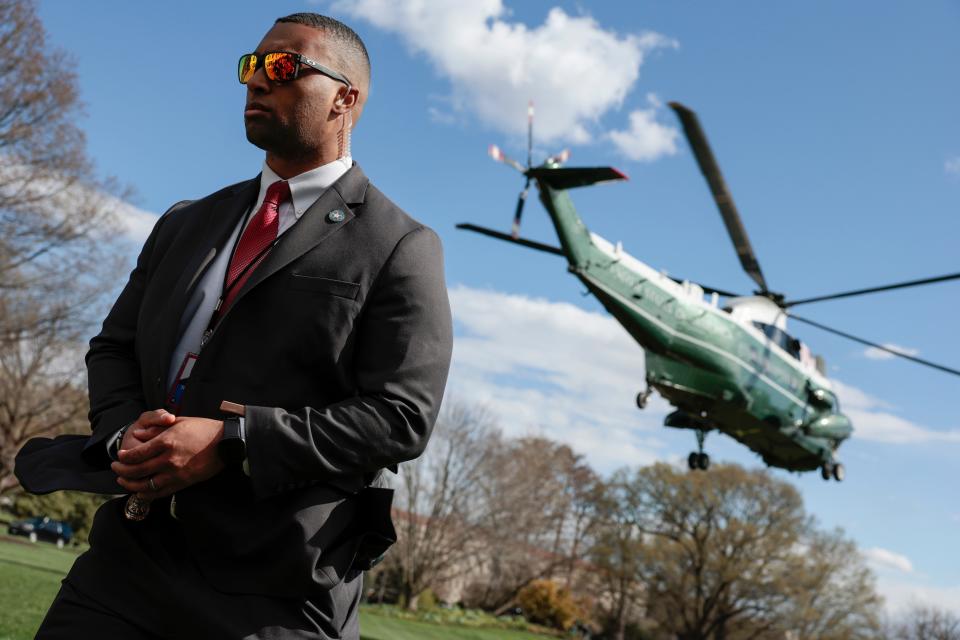 A Secret Service Agent looks on as Marine One, carrying President Joe Biden, lifts off from the South Lawn of the White House on April 1.