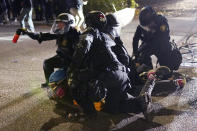 Portland police officers make an arrest while dispersing protesters in front of the Multnomah County Sheriff's Office early in the morning on Saturday, Aug. 8, 2020 in Portland, Ore. (AP Photo/Nathan Howard)