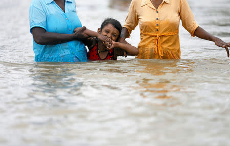 A girl reacts as her family members walks her through a flooded road in Kaduwela, Sri Lanka May 20, 2016. REUTERS/Dinuka Liyanawatte