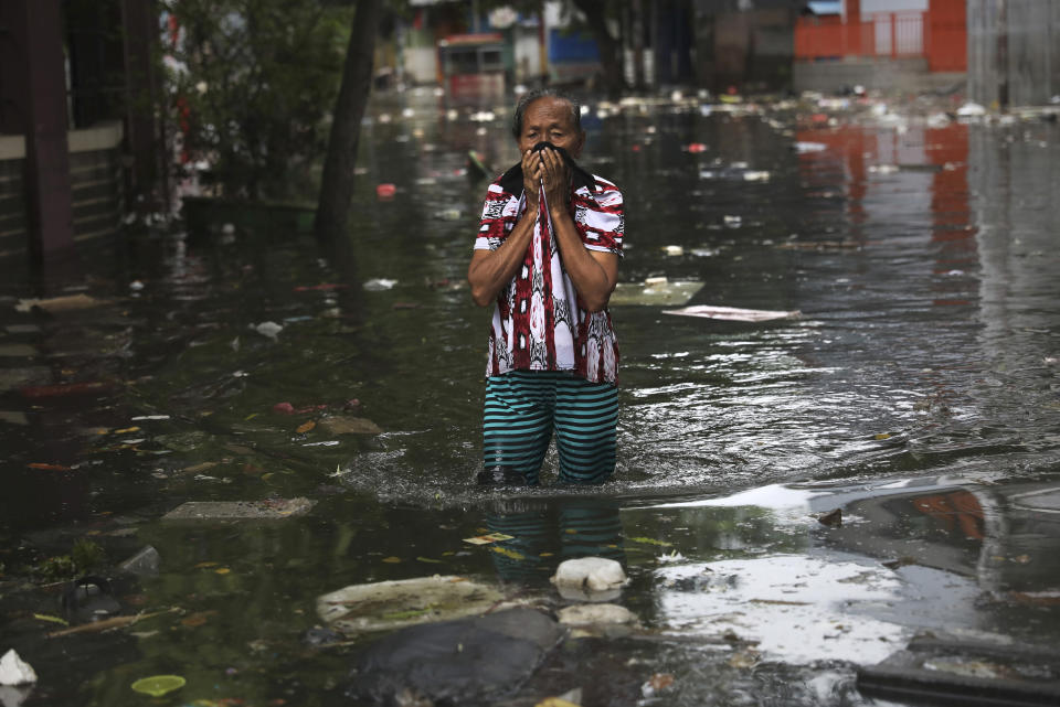 A woman reacts as she wades flood water in Jakarta, Indonesia, Saturday, Jan. 4, 2020. Monsoon rains and rising rivers submerged parts of greater Jakarta and caused landslides in Bogor and Depok districts on the city's outskirts as well as in neighboring Lebak, which buried a number of people. (AP Photo/Dita Alangkara)