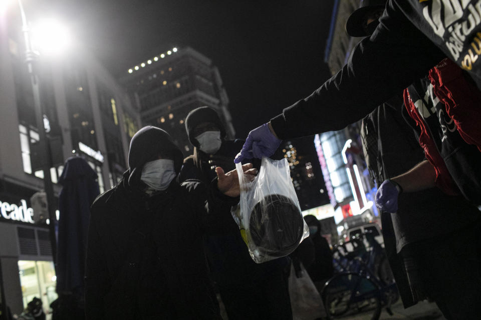 Men wearing protective masks receive warm plates of food from volunteers with Muslims Giving back at Herald Square in New York, on Saturday, April 25, 2020. Some of the food comes from donors like Hamza Deib, the 28-year-old owner of Brooklyn's Taheni Mediterranean Grill. The halal food he donates is the same that he serves in his restaurant -- on one night, rice, chicken, mixed vegetables and falafel for vegetarians. (AP Photo/Wong Maye-E)