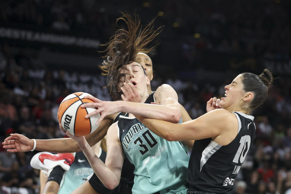 New York Liberty forward Breanna Stewart (30) grabs a rebound over Las Vegas Aces center A'ja Wilson and guard Kelsey Plum during the first half of a WNBA Semifinal basketball game, Sunday, Oct. 6, 2024, in Las Vegas. (AP Photo/Ian Maule)