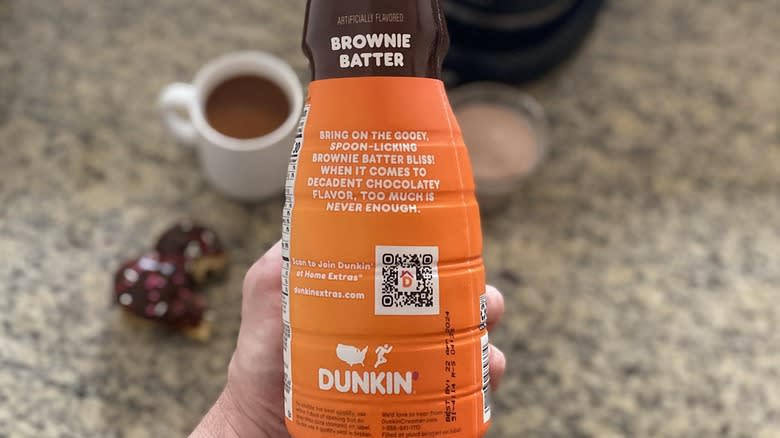 Hand holding Dunkin' creamer bottle