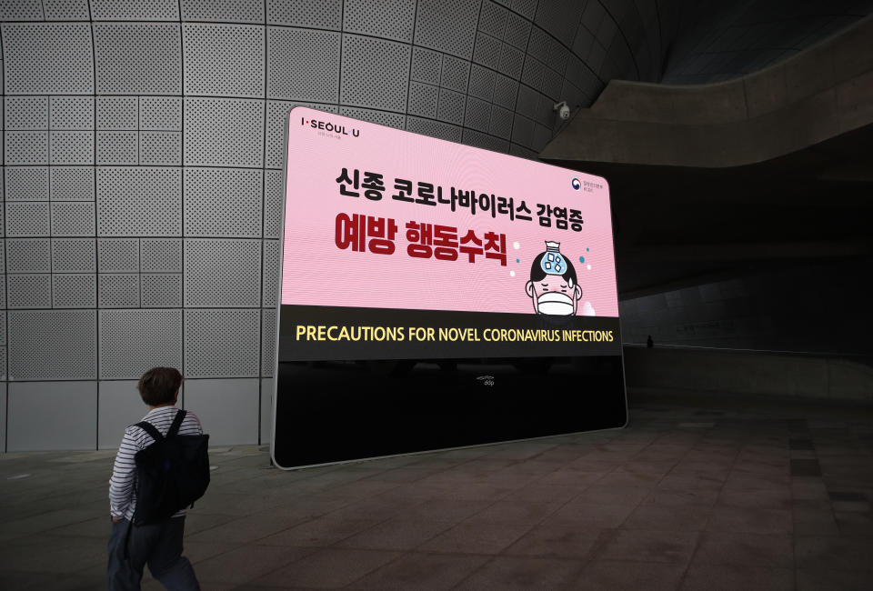 A man wearing a face mask walks by a screen showing precautions against the new coronavirus in Seoul, South Korea, Tuesday, May 12, 2020. (AP Photo/Lee Jin-man)