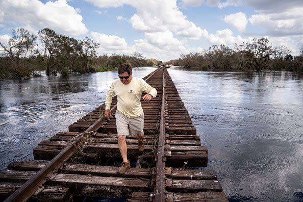 Mack Martin walks along train tracks surrounded by floodwaters at the Peace River on October 4, 2022, in Arcadia, Florida. Fifty miles inland, and nearly a week after Hurricane Ian made landfall on the Gulf Coast of Florida, the record-breaking floodwaters in the area are receding to reveal the full effects of the storm.