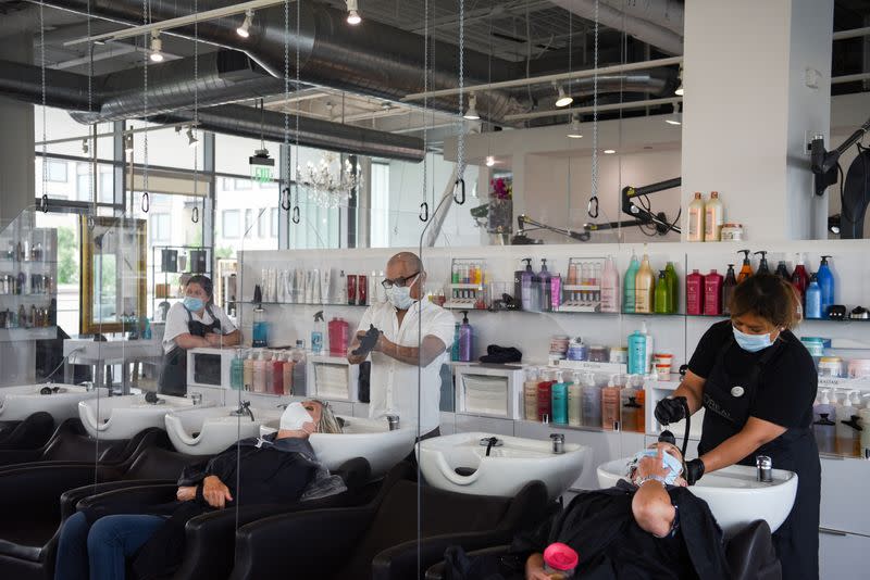 Women are separated by dividers as they have their hair washed after social distancing guidelines to curb the spread of the coronavirus disease (COVID-19) are relaxed, at Bella Rinova