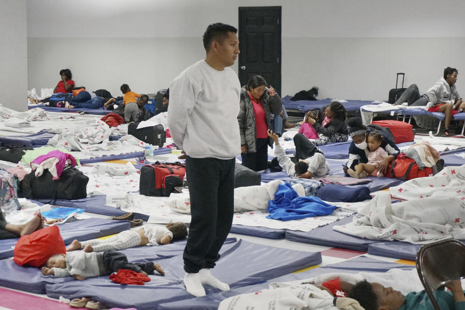 Ronny, a 26-year-old asylum-seeker from Venezuela, stands for a Catholic Mass celebrated by visiting priests in the large room where migrants rest and sleep at the Humanitarian Respite Center in McAllen, Texas, on Dec. 15, 2022. Ronny, his wife, and their kids, aged 3 and 10 months, traveled more than three months before crossing near El Paso and turning themselves in to U.S. officials, who flew them over to McAllen because El Paso "was collapsed" with new arrivals, Ronny said. (AP Photo/Giovanna Dell'Orto)