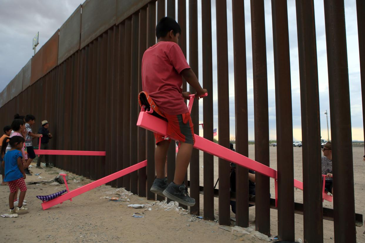 <p>Families play with the seesaw over the Mexican border with US at the Anapra zone in Ciudad Juarez</p> (AFP via Getty Images)