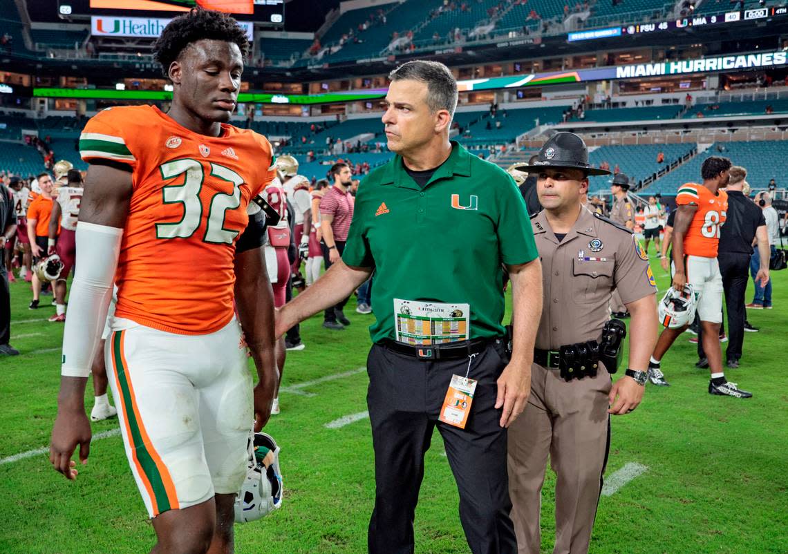 Miami Hurricanes head coach Mario Cristobal walks off the field with defensive lineman Nyjalik Kelly (32) after the Florida State Seminoles defeat the Canes 45-3 at Hard Rock Stadium in Miami Gardens on Saturday, November 5, 2022.