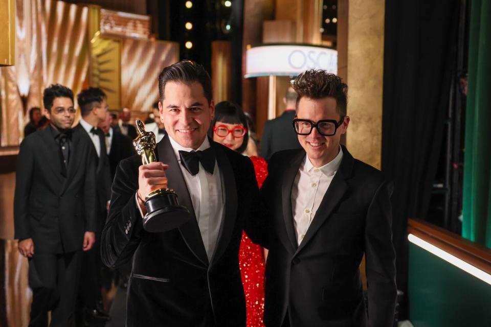 Men in tuxedos, one holding an Oscar, backstage at the 95th Academy Awards at the Dolby Theatre.