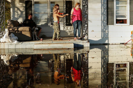 Local residents gather on their front porch as a child shoots a BB gun while they seek refuge from flood waters due to Hurricane Matthew in Lumberton, North Carolina, October 12, 2016. REUTERS/Carlo Allegri