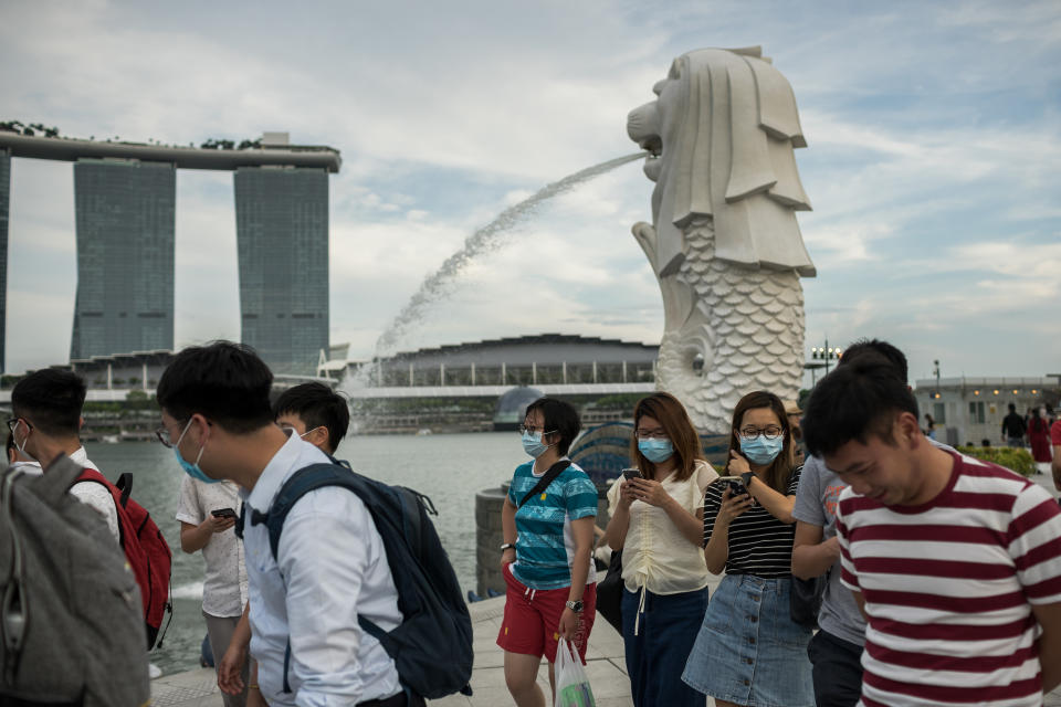 SINGAPORE - 2020/02/12: People wearing protective surgical masks walk along the Merlion Park, a major tourist attraction in Singapore. Singapore declared the Coronavirus outbreak alert as Code Orange on February 7, 2020. (Photo by Maverick Asio/SOPA Images/LightRocket via Getty Images)