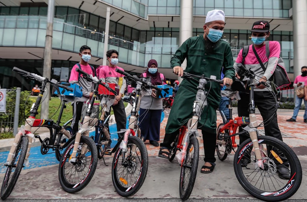 Ustaz Ebit Lew (in green) presenting the lightweight bicycles to help the delivery walkers with their food orders around Kuala Lumpur. — Picture via Facebook/EbitLew