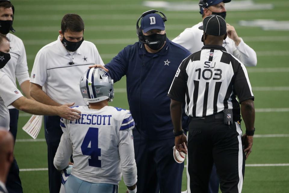 Dallas Cowboys quarterback Dak Prescott (4) is checked on by staff and head coach Mike McCarthy, second from right, who talks with field judge Eugene Hall (103) in the second half of an NFL football game against the Atlanta Falcons in Arlington, Texas, Sunday, Sept. 20, 2020. (AP Photo/Ron Jenkins)