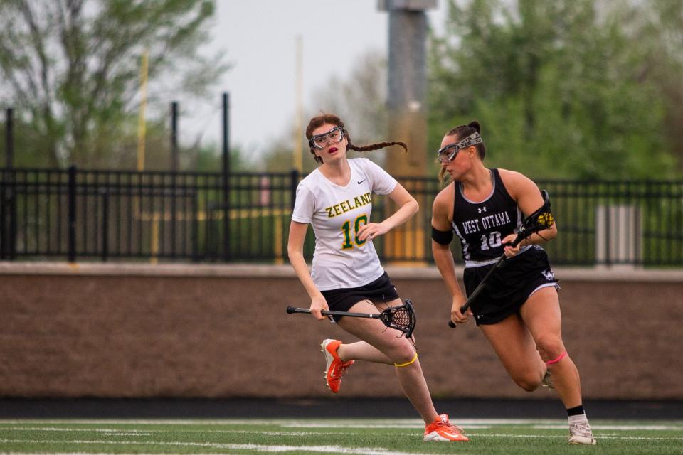 West Ottawa's Ella Spooner takes the ball up the field past Zeeland's Saige Canfield during a game between Zeeland and West Ottawa Wednesday, May 11, 2022, at Zeeland High School. 