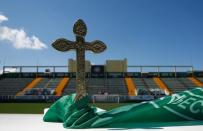 A cross is pictured over a flag of Chapecoense atop an altar prepared for a tribute at the Arena Conda stadium in Chapeco, Brazil. REUTERS/Ricardo Moraes