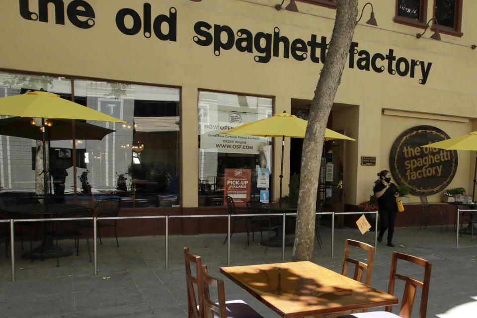 A woman exits the Old Spaghetti Factory restaurant with a take-out order Monday, July 6, 2020, in San Jose, Calif. The Independence Day weekend saw one of Santa Clara County's largest increases in COVID-19 cases to date, which came as the state of California denied the county's application for further reopening of businesses and activities. (AP Photo/Ben Margot)