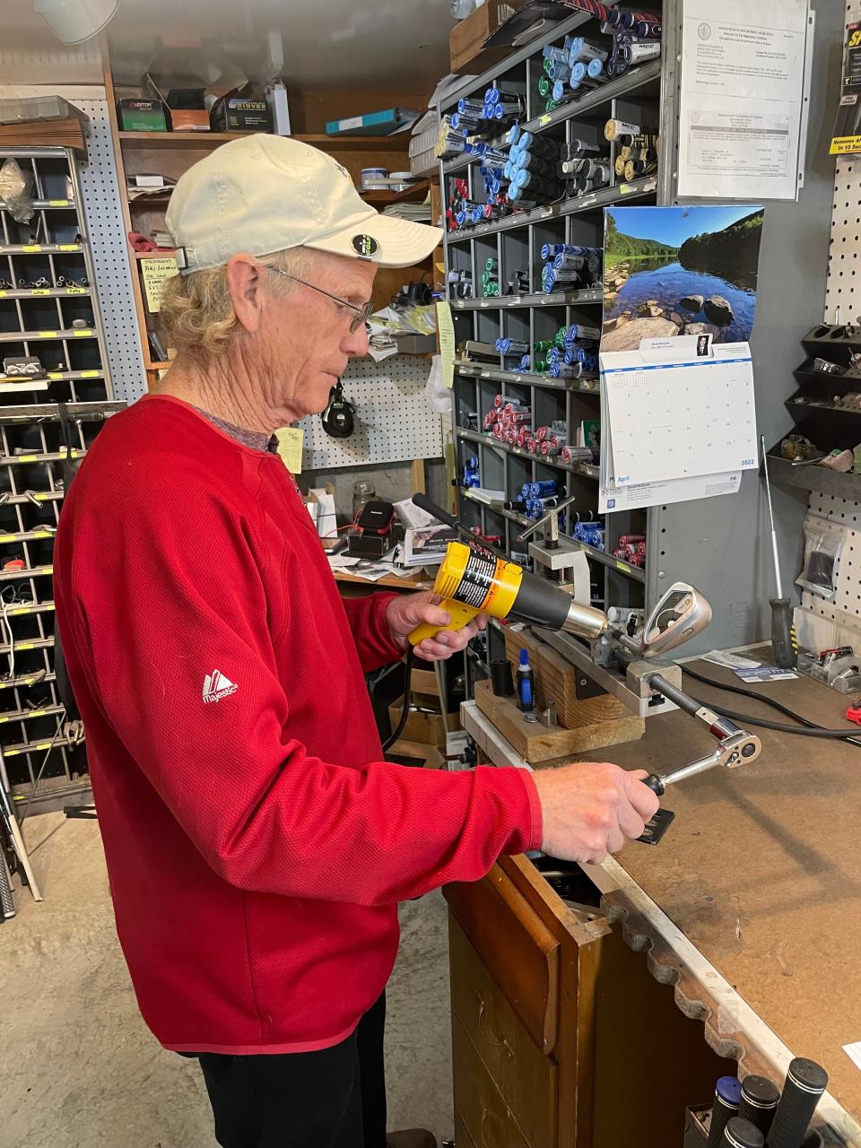 Don Sharron is removing the club head from a shaft in his Grip & Rip It Golf work shop in the basement of his home in Boylston.