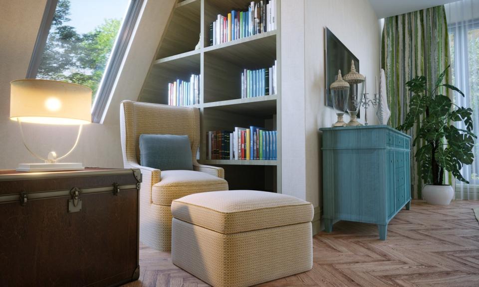 A reading area in attic bedroom, includes a chair, an inset bookcase and books. 