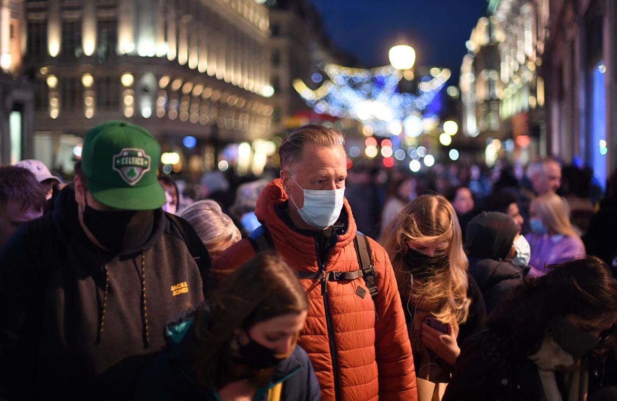 Shoppers, some wearing face coverings, cross Oxford Street in central London on December 4, 2021, as compulsory mask wearing in shops has been reintroduced in England as fears rise over the Omicron variant of Covid-19. (Photo by Daniel LEAL / AFP) (Photo by DANIEL LEAL/AFP via Getty Images)