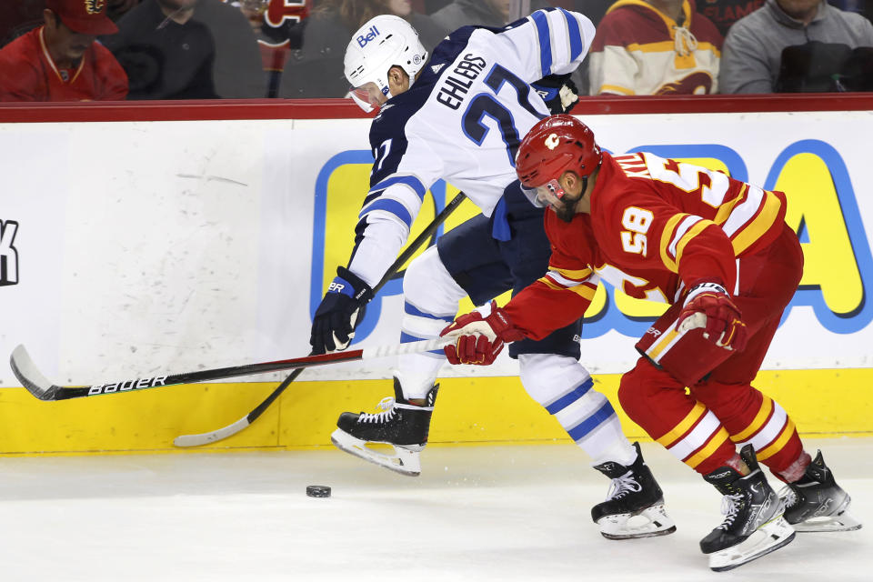 Winnipeg Jets' Nikolaj Ehlers, left, works for the puck against Calgary Flames' Oliver Kylington during the second period of an NHL hockey game Saturday, Nov. 27, 2021, in Calgary, Alberta. (Larry MacDougal/The Canadian Press via AP)