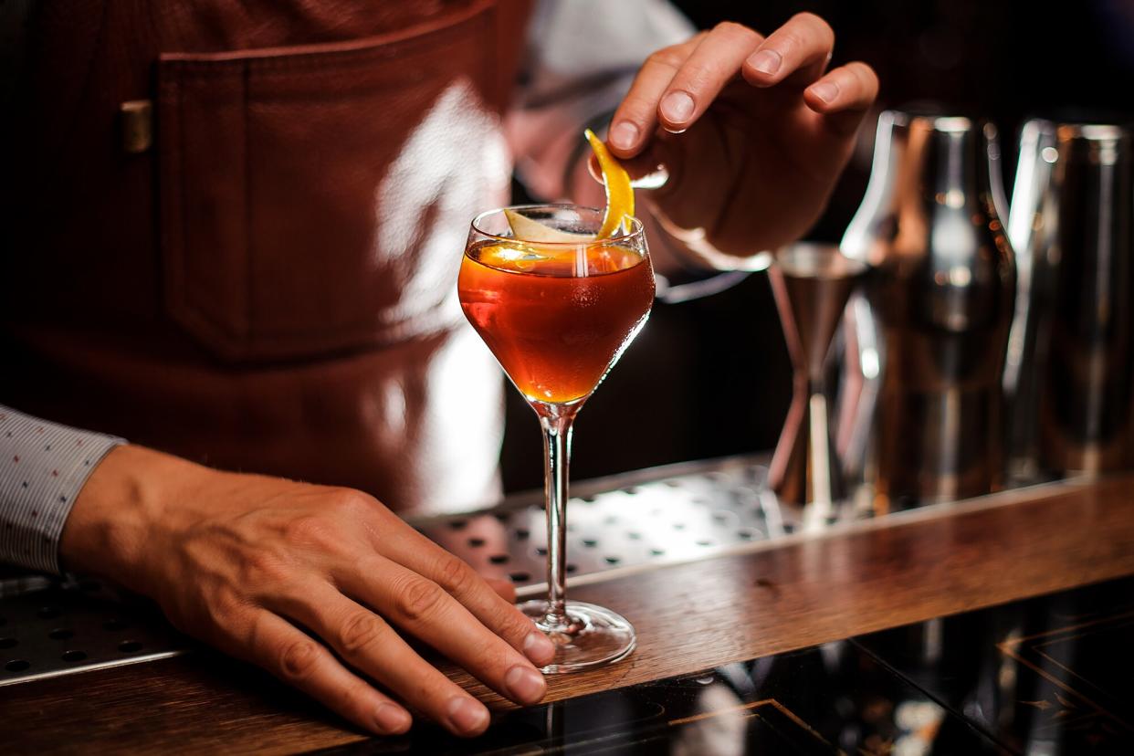 A bartender adds garnish to a cocktail