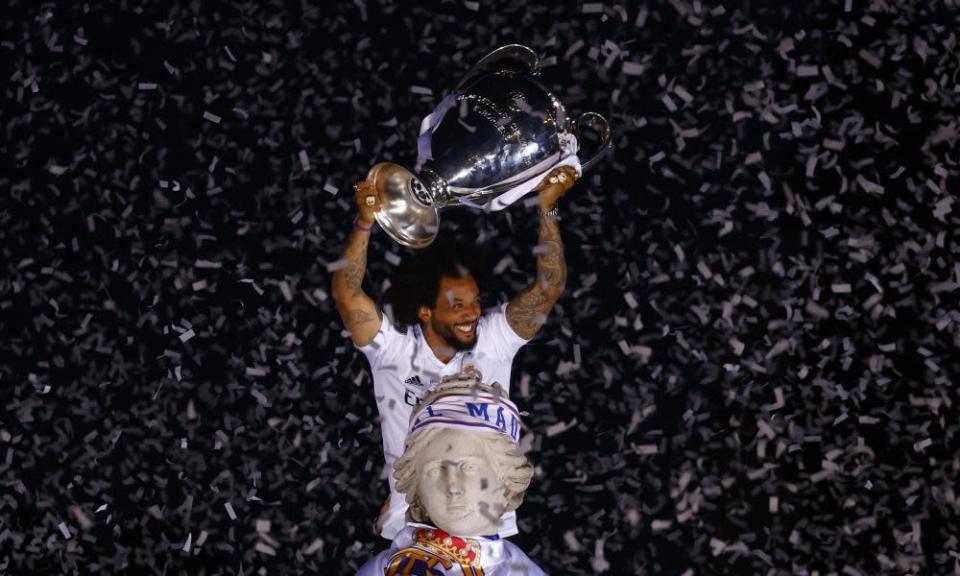Marcelo poses with the Champions League trophy on top of a fountain with confetti falling all around him