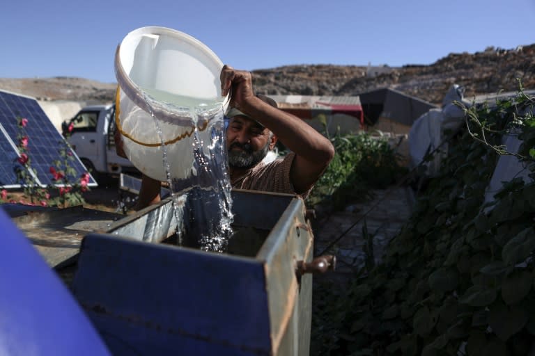 Abdelkarim transfère de l'eau dans un réservoir près de sa tente dans un camp pour personnes déplacées près de Sarmada, dans la province d'Idleb dans le nord de la Syrie, le 28 juin 2024 (AAREF WATAD)