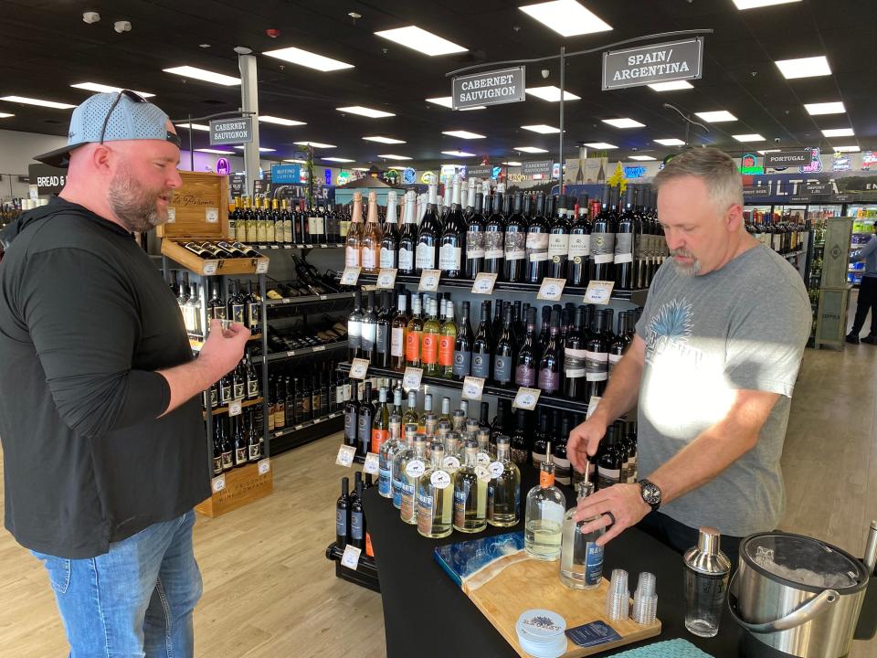 Regret Distillery owner Rob Lombardi, right, offers a sample of his craft agave spirit to a customer at Liquor World in South Easton at a tasting on Thursday, March 8, 2024.