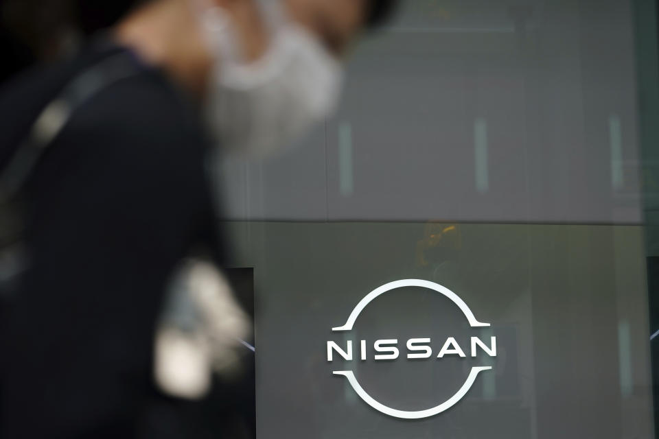 A man wearing a face mask to to help curb the spread of the coronavirus walks by the logo of Nissan seen at the automaker's showroom in Tokyo Tuesday, May 11, 2021. Nissan reduced its losses for January-March, compared to last year, as restructuring efforts kicked in, despite the sales damage from the coronavirus pandemic, the Japanese automaker said Tuesday. (AP Photo/Eugene Hoshiko)