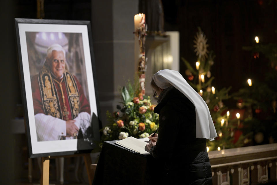 A person signs a book of condolence for Pope Emeritus Benedict XVI at the Saint Magdalena church in Altoetting, Germany, Saturday, Dec. 31, 2022. Pope Emeritus Benedict XVI, the German theologian who will be remembered as the first pope in 600 years to resign, has died, the Vatican announced Saturday. He was 95. (AP Photo/Andreas Schaad)