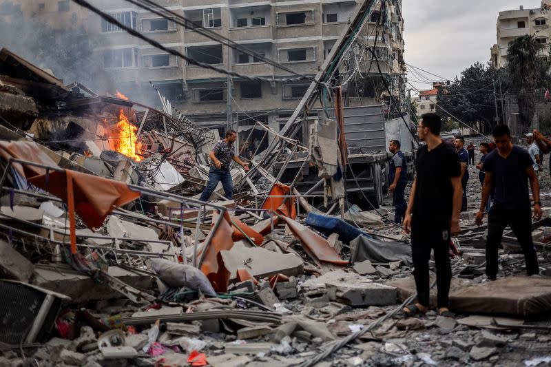 Palestinos observan un incendio entre los escombros de un edificio residencial dañado, tras los ataques israelíes, en Gaza